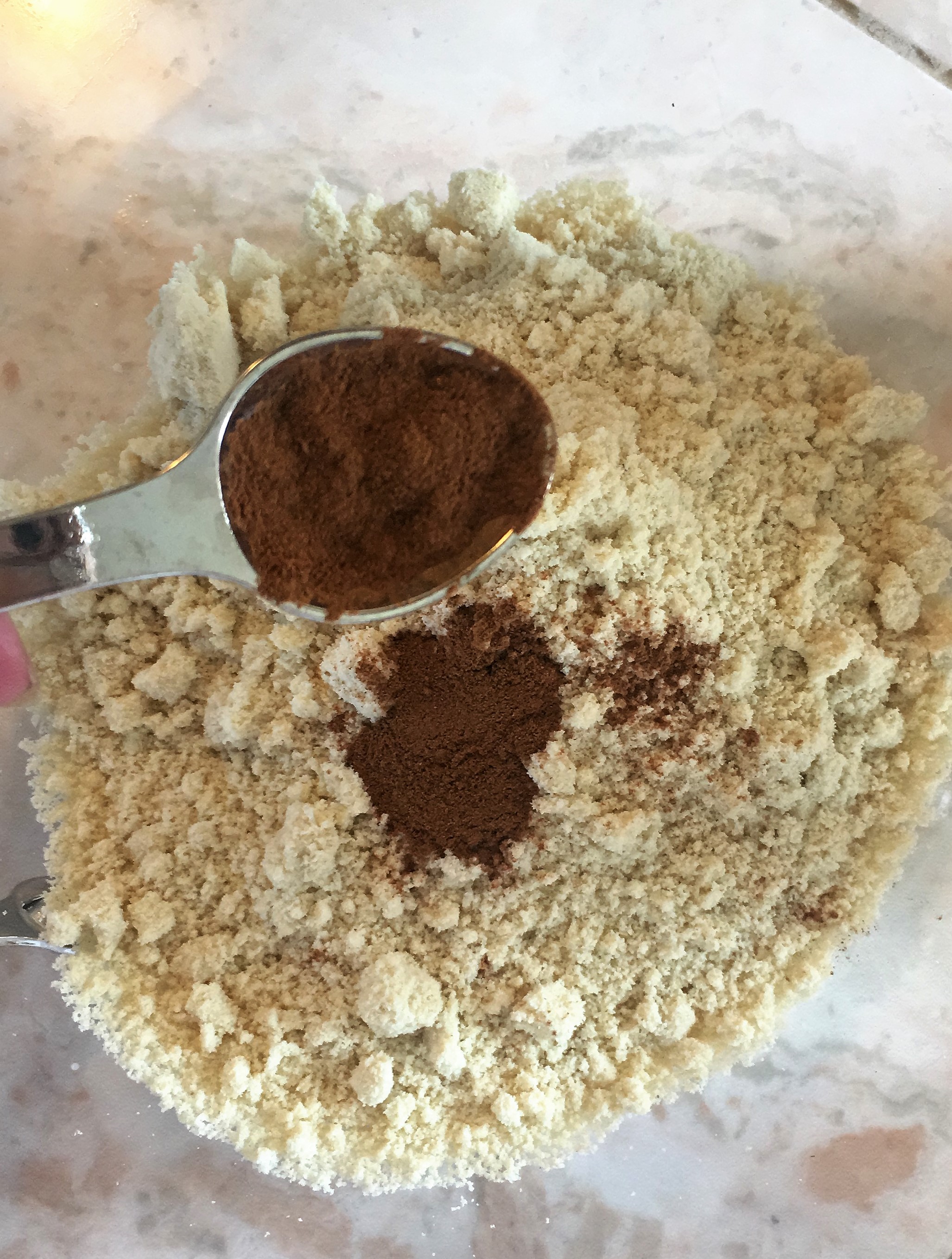 Flour in a bowl teaspoon pouring cinnamon into the bowl