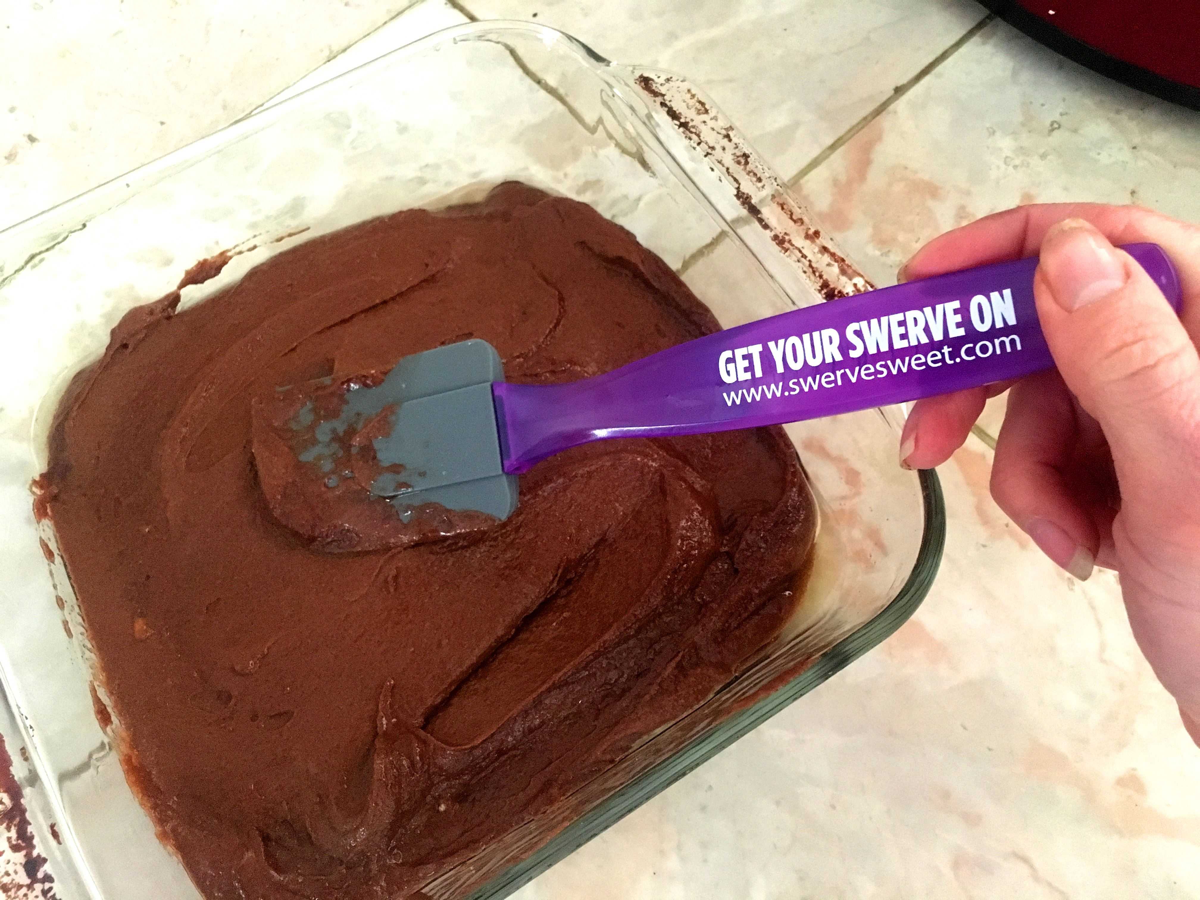 Brownies batter being spread in a glass container