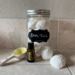 DIY DIshwasher Tabs in a mason jar two tabs on counter doterra lemon bottom in front and a lemon 1 tbsp lemon spoon on the counter.