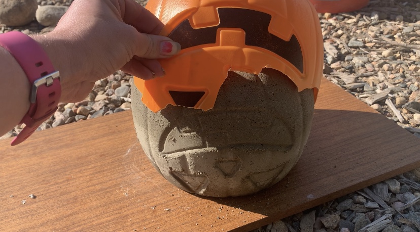 Concrete upside down pulling the rest of the broken plastic pumpkin off the concrete. 
DIY Concrete Pumpkin these are so fun and easy to make! #diy #diyhalloween #diyfalldecor #diyconcrete pumpkin www.innovativehealthfitness.com