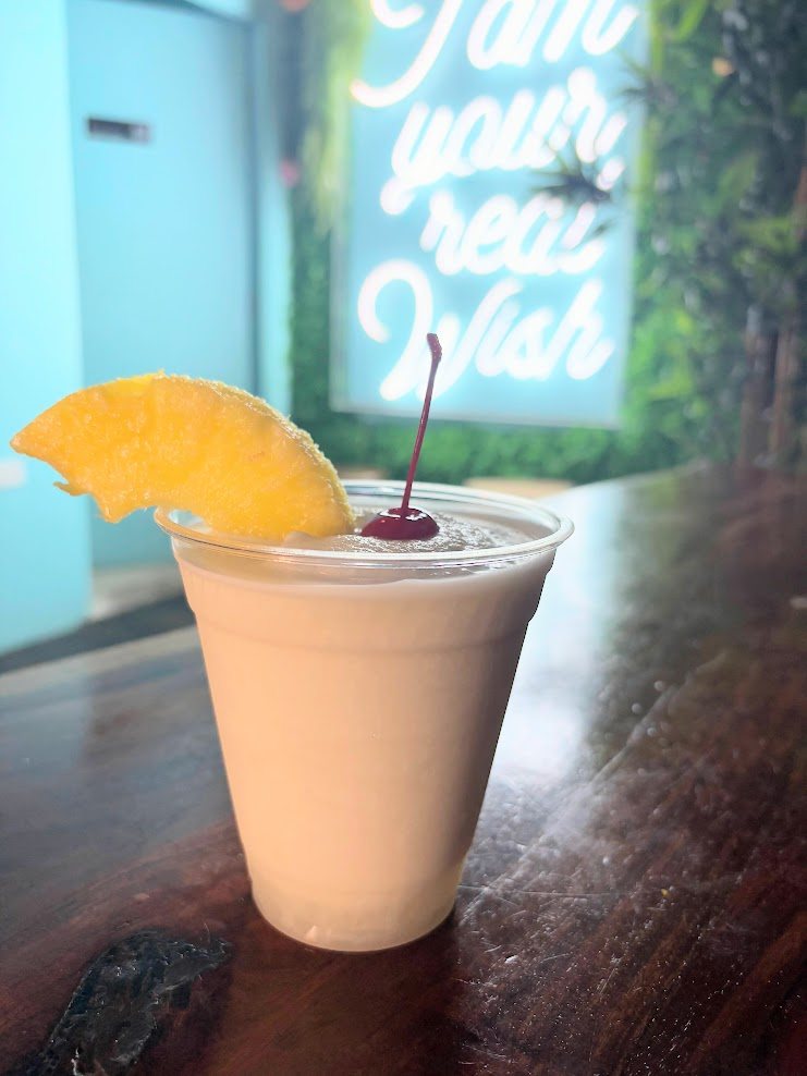 A tropical Piña Colada topped with fresh fruit garnishes and a straw, served directly inside a carved whole pineapple at Piña Loka in Old San Juan, Puerto Rico.