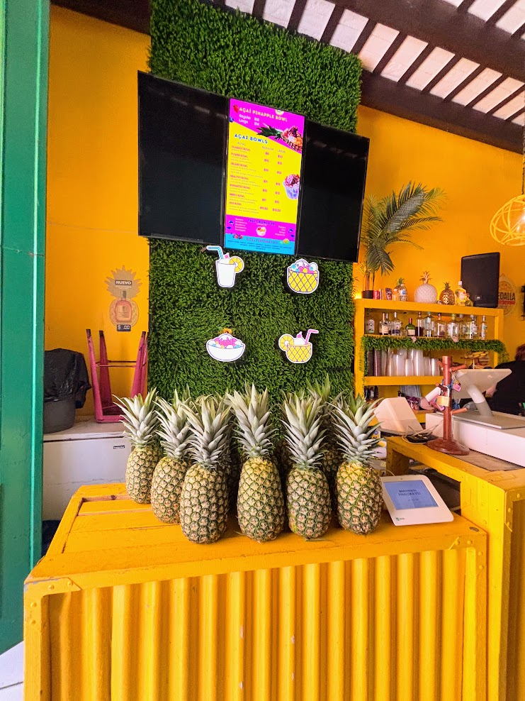 A tropical Piña Colada topped with fresh fruit garnishes and a straw, served directly inside a carved whole pineapple at Piña Loka in Old San Juan, Puerto Rico.