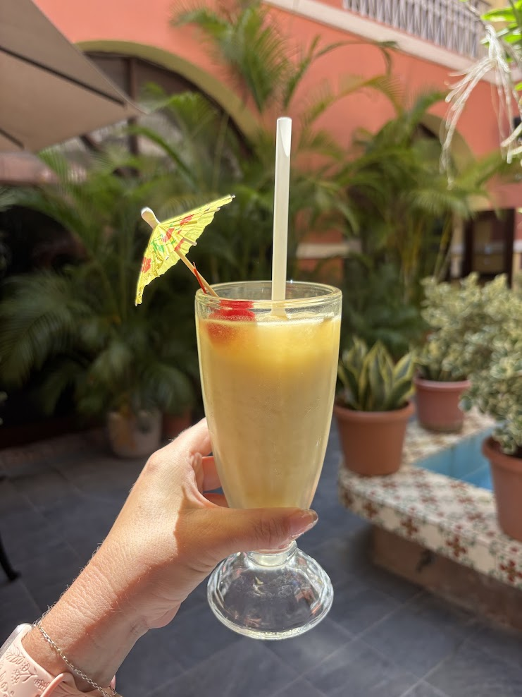Frosted glass of Piña Colada topped with a cherry in the lush open-air courtyard at Barrachina in San Juan.